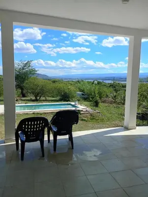 two chairs sitting on a porch with a view of a pool at Casa en sierras de cordoba in San Roque