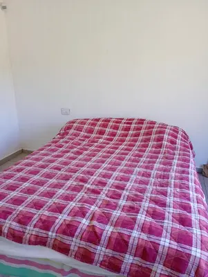 a bed with a red and white blanket on it at Casa en sierras de cordoba in San Roque