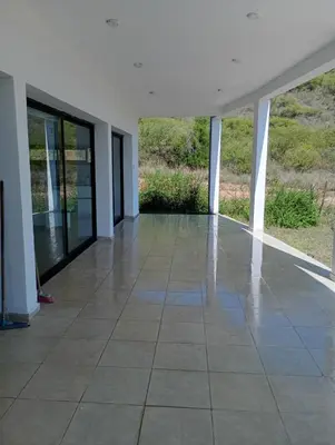 an empty room with a tiled floor and windows at Casa en sierras de cordoba in San Roque