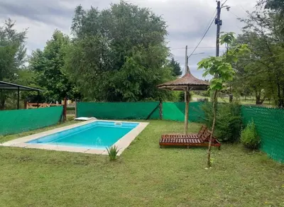 a swimming pool in a yard with a umbrella and chairs at Los Peranzzi-Casa Serrana in Los Reartes