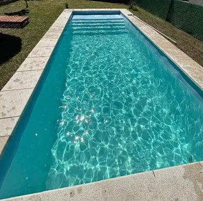 a swimming pool with blue water in a yard at Los Peranzzi-Casa Serrana in Los Reartes