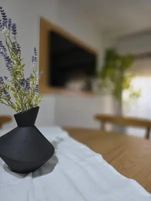 a black vase with flowers sitting on a table at Vissia Cba in Cordoba