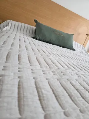 a white bed with a green pillow on it at Vissia Cba in Cordoba