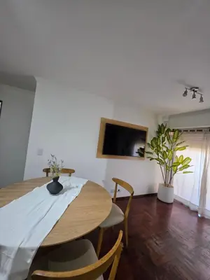a dining room table with chairs and a tv on the wall at Vissia Cba in Cordoba