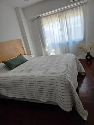 a bedroom with a bed with a white comforter and a window at Vissia Cba in Cordoba