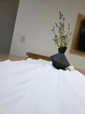 a black vase with flowers sitting on top of a bed at Vissia Cba in Cordoba