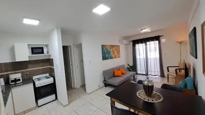 a kitchen and a living room with a table in a room at Dpto a estrenar Asador Pileta Cochera propia Terraza privada con vista a sierras Seguridad 24 hs Av Colón Alberdi Ubicación estratégica H Clínicas Kempes Shopping Carlos Paz in Cordoba