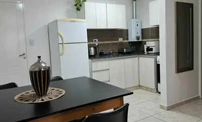 a kitchen with a black table and a refrigerator at Dpto a estrenar Asador Pileta Cochera propia Terraza privada con vista a sierras Seguridad 24 hs Av Colón Alberdi Ubicación estratégica H Clínicas Kempes Shopping Carlos Paz in Cordoba