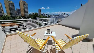 a patio with a table and chairs on a balcony at Dpto a estrenar Asador Pileta Cochera propia Terraza privada con vista a sierras Seguridad 24 hs Av Colón Alberdi Ubicación estratégica H Clínicas Kempes Shopping Carlos Paz in Cordoba