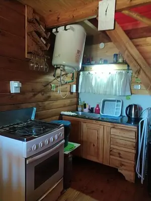 a kitchen with a stove top oven in a cabin at La Soñada in Santa Rosa de Calamuchita