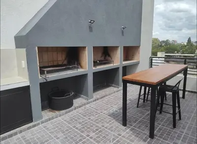 a kitchen with a table and a fireplace on a roof at Apart Miralejos 17 villa carlos Paz in Cordoba