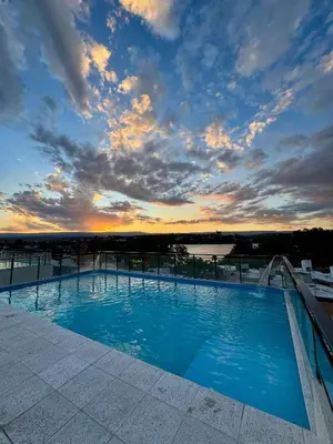 a swimming pool on top of a building with a sunset at Apart Miralejos 17 villa carlos Paz in Cordoba