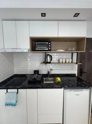 a white kitchen with a sink and a microwave at Apart Miralejos 17 villa carlos Paz in Cordoba