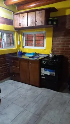 a kitchen with a stove and a yellow wall at Cabaña los algarrobos in Mina Clavero