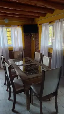 a dining room with a wooden table and chairs at Cabaña los algarrobos in Mina Clavero
