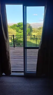 an open door to a deck with a view at Cabaña los algarrobos in Mina Clavero
