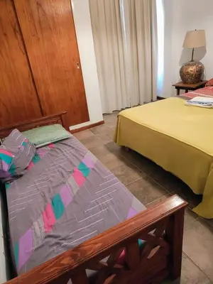 a room with two beds and a bench in it at La Escondida, casa completa para 6 en Calamuchita in La Cruz