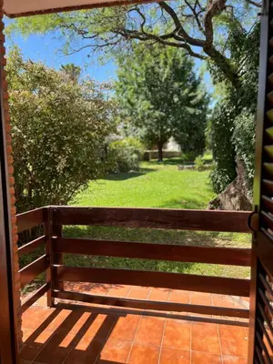 a wooden bench on a porch with a field of grass at Hosteria Abuelo Juan in Mina Clavero