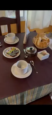 a table with plates and cups and a bowl of bread at Hosteria Abuelo Juan in Mina Clavero