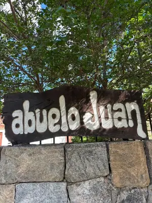 a sign on top of a stone wall at Hosteria Abuelo Juan in Mina Clavero