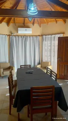 a dining room with a table with chairs and white curtains at La Bonita, casa en Villa de Merlo, SL in Merlo