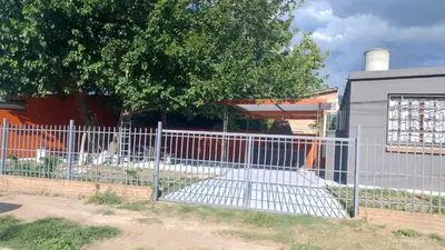 a fence in front of a building with a tree at La Bonita, casa en Villa de Merlo, SL in Merlo