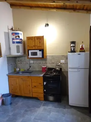 a kitchen with a stove and a white refrigerator at Cabañas Antillanca in Luyaba
