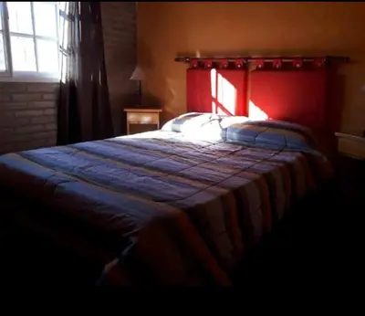 a bedroom with a bed with a red headboard and a window at Cabañas Antillanca in Luyaba