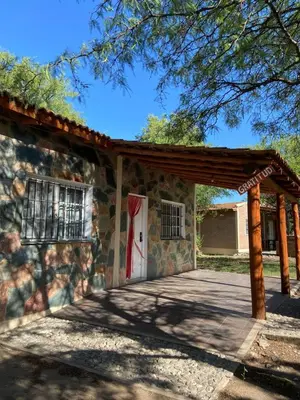 a stone house with a red door and a porch at Cabañas Antillanca in Luyaba