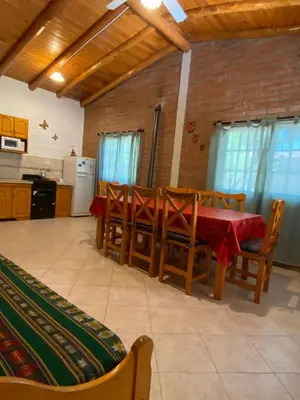 a dining room with a table and chairs and a kitchen at Cabañas Antillanca in Luyaba