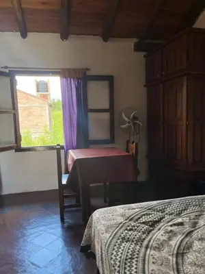 a bedroom with a bed and a table and a window at Casa de iris in Mina Clavero