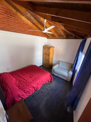 a bedroom with a red bed and a chair at Deptos Mabelita in Mina Clavero