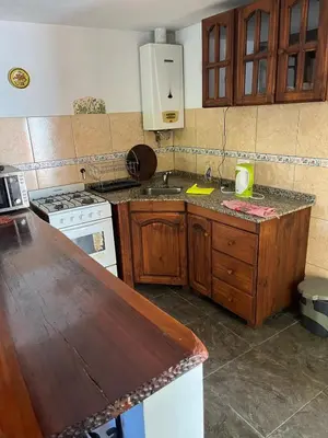 a kitchen with wooden cabinets and a counter top at Deptos Mabelita in Mina Clavero