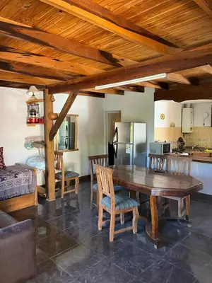 a kitchen and dining room with a wooden table and chairs at Deptos Mabelita in Mina Clavero