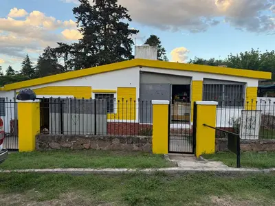 a yellow and white building with a fence at Casa en Villa Carlos Paz in Estancia Vieja
