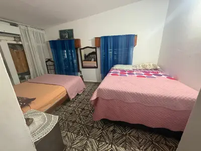 two beds in a room with blue curtains at Casa en Villa Carlos Paz in Estancia Vieja