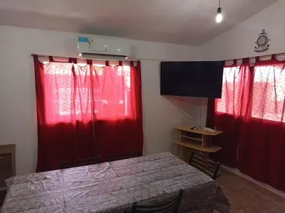 a room with red curtains and a table and a television at Casa Agüero in Villa Cura Brochero