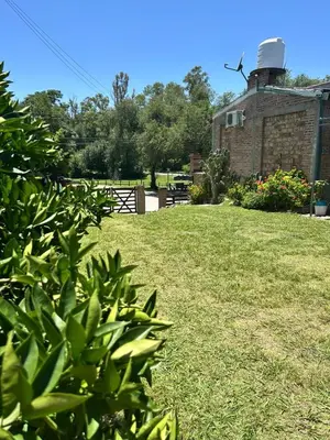 a grassy yard with a building with a water tank at Los Jazmines in Alta Gracia