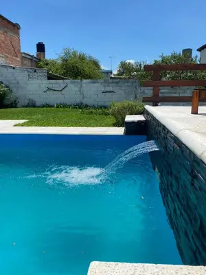 a pool of blue water with a fountain at Los Jazmines in Alta Gracia