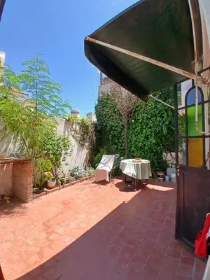 a patio with a table and a green umbrella at Casa Corna in Río Cuarto