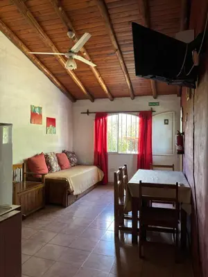 a living room with a bed and a table and a window at Complejo Alto Paraiso in Villa Cura Brochero