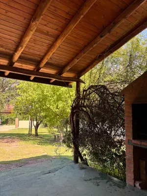 a porch with a wooden roof with a tree at Complejo Alto Paraiso in Villa Cura Brochero