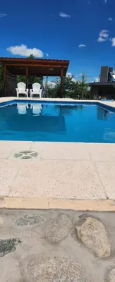 a swimming pool with two chairs and a gazebo at Aire de montaña in Quebrada de los Pozos