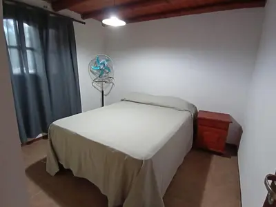 a bedroom with a bed with a fan on the wall at Complejo LA ADELAIDA in Mina Clavero