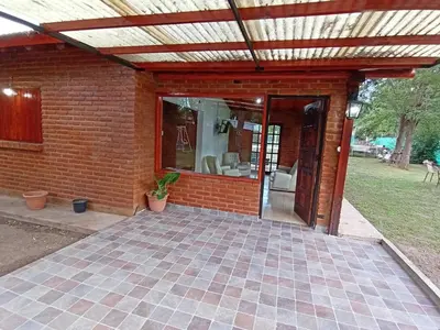 an outdoor patio with awning and a brick wall at Complejo LA ADELAIDA in Mina Clavero
