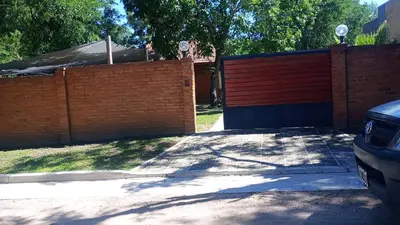 a brick fence and a driveway with a garage at Complejo LA ADELAIDA in Mina Clavero