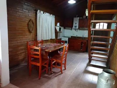 a kitchen with a wooden table and chairs at Complejo LA ADELAIDA in Mina Clavero