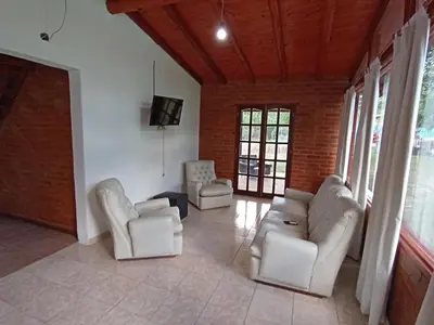 a living room with two white couches and a tv at Complejo LA ADELAIDA in Mina Clavero