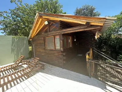 a wooden cabin with two benches on a deck at Cabaña con pileta en Villa Carlos Paz in Villa Carlos Paz