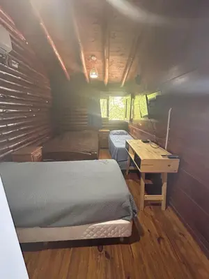 a small room with two beds and a desk in it at Cabaña con pileta en Villa Carlos Paz in Villa Carlos Paz